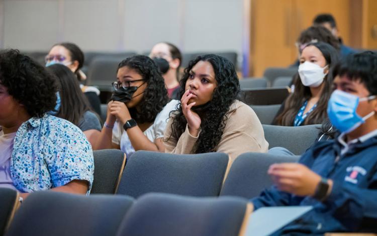 A group of CURE interns sit in the audience, listening to presentations.